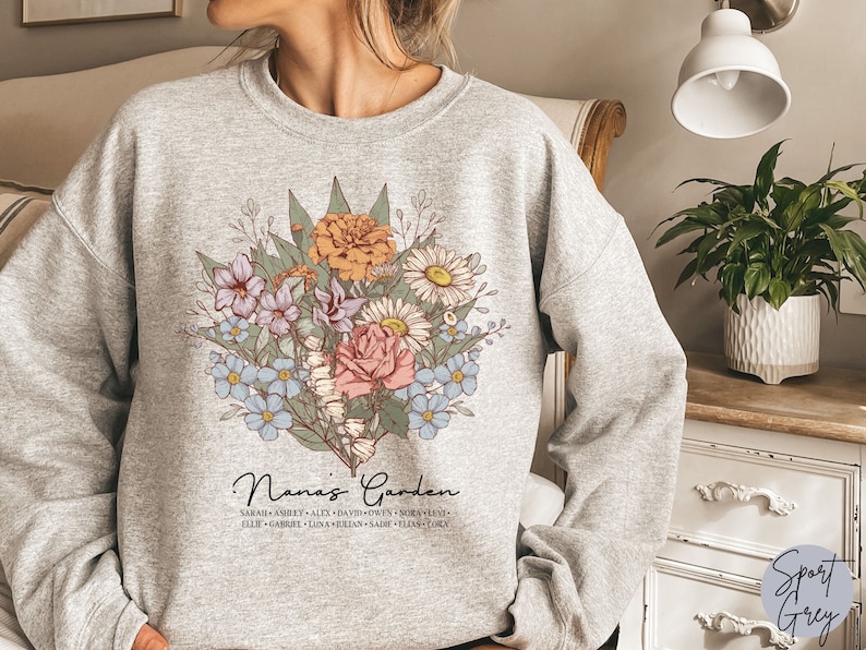 May include: A gray sweatshirt with a floral design and the text "Nana's Garden" with a list of names underneath.