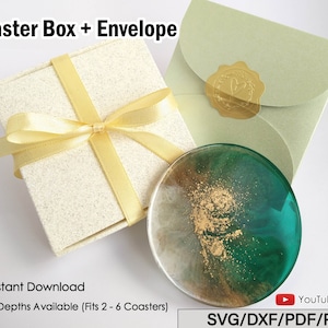 Op de afbeelding: Een onderzetterset met een doos en een envelop. De doos is crèmekleurig met een gele lint. De envelop is lichtgroen met een gouden zegel. Er is ook een ronde onderzetter met groene, gouden en witte accenten. De tekst op de afbeelding luidt "Coaster Box + Envelope".