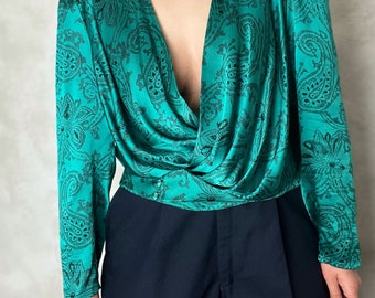 May include: A teal blue long-sleeved blouse with a paisley print and a deep V-neckline.