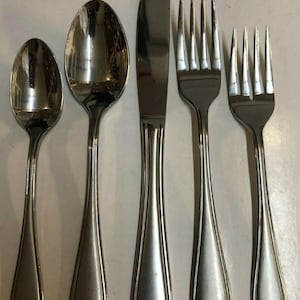 May include: Set of five silver-toned flatware pieces, including a knife, two forks, and two spoons. The pieces have a simple, elegant design with a rounded handle.