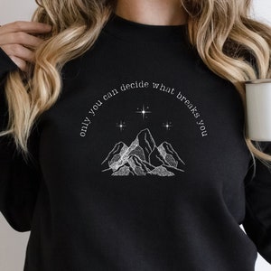 May include: Black sweatshirt with a white graphic of mountains and stars. The text "only you can decide what breaks you" is written in a curved arc above the mountains.