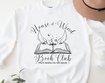 May include: White sweatshirt with a black graphic design of an open book with wings and mountains. The text "House of Wind Book Club + SMUTT BOOKS ON THE HOUSE +" is printed below the graphic.