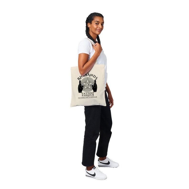 May include: A white tote bag with black text and a graphic of two hands making the 'rock on' hand gesture. The text reads 'Riff-Rands Tattoo Parlour Tattoos for a Rebellion'.