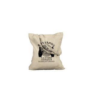 May include: A beige canvas tote bag with black text and a graphic design. The text reads "Rhysands Tattoo Parlour Tattoos for a Bargain".