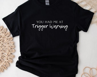 May include: Black t-shirt with white text that reads "You had me at trigger warning."