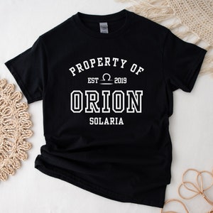 May include: Black t-shirt with white text that reads "PROPERTY OF EST. ♎ 2019 ORION SOLARIA"