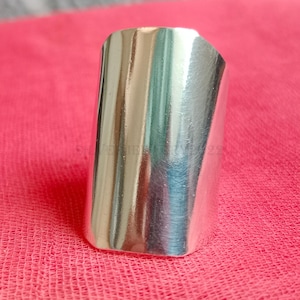 May include: A silver, rectangular-shaped ring with a smooth, polished finish.