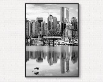 May include: Monochrome framed print of a city skyline with skyscrapers and a marina with sailboats. The buildings are reflected in the water, and a bird is in flight. The image is a black and white photograph.