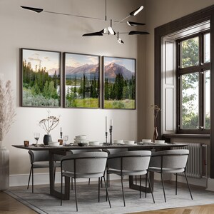 May include: A dining room scene featuring a dark wood table set with white dishes, candles, and glassware. Gray upholstered chairs with black metal frames surround the table. Three framed landscape prints hang above the table.