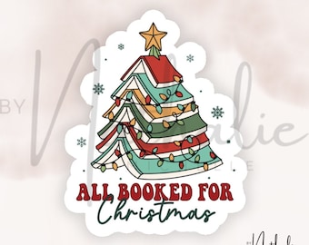 May include: A sticker featuring a Christmas tree made of stacked books with a star on top and a string of lights. The text "All Booked for Christmas" is below the tree.