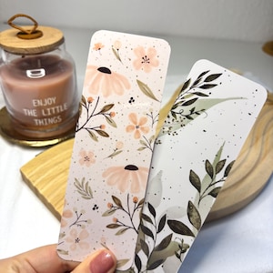 May include: Two floral bookmarks, one with a pink and white floral pattern and the other with a green and white leaf pattern.