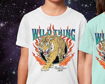 May include: A white t-shirt and a light green t-shirt, each featuring a graphic print of a tiger emerging from a dark circle surrounded by orange flames. Above the tiger, the text reads WILD THING, and below it, the text reads Rock Tour 1989.