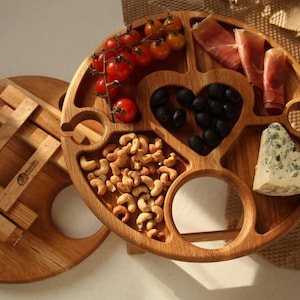 Mesa de picnic plegable de madera con compartimentos para aperitivos y ranuras para copas de vino, tabla de vino y quesos hecha a mano para reuniones al aire libre.