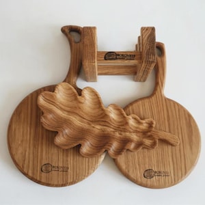 May include: Two round wooden serving boards with handles, a leaf-shaped wooden bowl, and a wooden stand. Each board and the stand feature a branded logo with the text BOROVETS. The items are crafted from light brown wood with visible grain.
