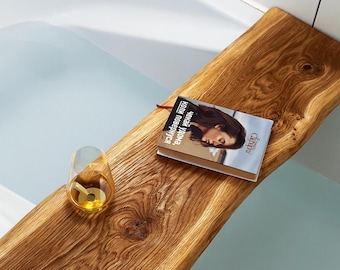 Peut inclure: Un plateau de bain en bois avec un livre intitulé "женская удова, когда повстречался" et un verre de liquide dessus. Le plateau est dans une baignoire avec de l'eau.
