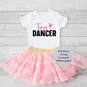 May include: A white baby onesie with the text "Tiny Dancer" in pink and black, featuring a ballerina graphic. Paired with a pink tutu skirt with a gold waistband, perfect for a young dancer.