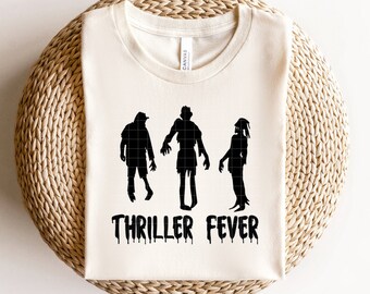May include: A white t-shirt with a black silhouette of three zombies and the text "Thriller Fever" in black dripping letters.