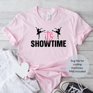 May include: Pink t-shirt with a black graphic of two dancers and the text "it's SHOWTIME".