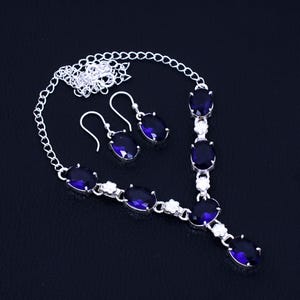 May include: A silver necklace and earrings set with a silver chain and oval-shaped blue gemstones.