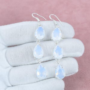 Puede incluir: Un par de pendientes de plata con tres piedras de ópalo en forma de lágrima en cada pendiente.