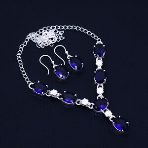 May include: A silver necklace and earrings set with a silver chain and oval-shaped blue gemstones.