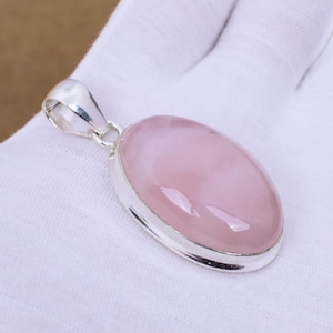 May include: A silver pendant featuring a large oval-shaped rose quartz gemstone. The pendant has a smooth, polished finish and a delicate silver bail.