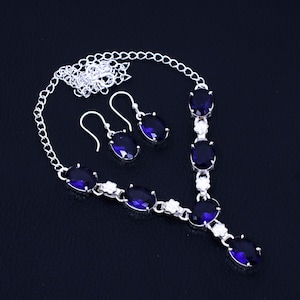May include: A silver necklace and earrings set with a silver chain and oval-shaped blue gemstones.