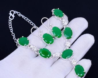 May include: A silver necklace and earrings set with green oval-shaped gemstones. The necklace has a pendant with a larger green gemstone.