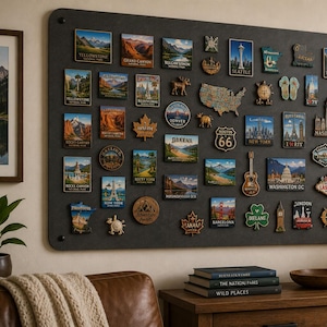 May include: A large rectangular dark gray magnetic display board mounted on a wall, covered with a collection of various souvenir magnets featuring landmarks, city names, national parks, and shapes like maps, animals, and symbols from many locations.