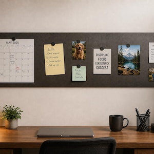 Op de afbeelding: Een lang, rechthoekig prikbord van donkergrijs vilt aan de muur, voorzien van een kalender voor mei 2025, een gele to-do lijst, een foto van een hond, een briefje met de tekst DISCIPLINE FOCUS CONSISTENCY SUCCESS, een berglandschap en een maaltijdplan.
