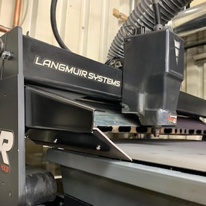 May include: A black Langmuir Systems Crossfire 4x8 XR CNC plasma cutting machine. The machine has a rectangular frame with the brand name and model number prominently displayed. The cutting head is visible, along with the cutting bed.