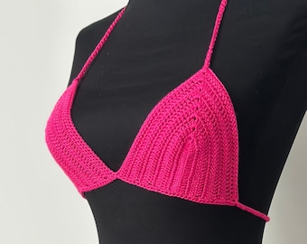 May include: A pink crocheted bikini top and bottom. The top is a triangle style with thin straps. The bottom is a high-waisted style with ties on the sides.