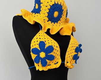 May include: Yellow crochet bikini set with blue flower accents. The set includes a bikini top, bikini bottom, and a matching sun hat.