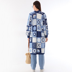 Può includere: Un lungo cardigan in crochet blu e bianco con un design a patchwork che presenta vari motivi floreali. Il cardigan ha una vestibilità rilassata e maniche lunghe.