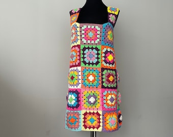 May include: A colorful crochet dress with a square pattern in shades of pink, purple, orange, yellow, green, and blue.