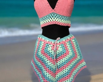 May include: A pink and green crochet bikini top and skirt set. The top is a halter style with a V-neckline. The skirt is a mini skirt with a crochet pattern.
