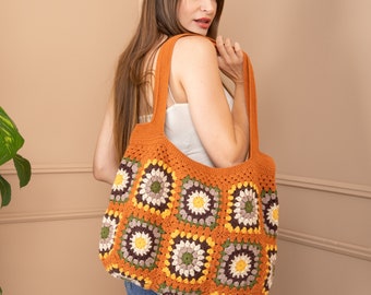 May include: A large, crocheted tote bag with a brown, orange, yellow, green, and white color scheme. The bag is made of squares with a floral pattern.