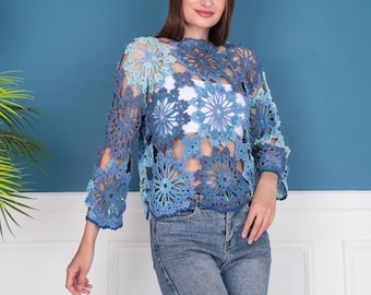 May include: A blue crochet top with a floral pattern. The top has long sleeves and a loose fit.