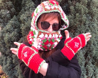 May include: A handmade crochet winter set featuring a hood, face covering, and fingerless gloves. The set is primarily red, with white and green accents. The hood has a floral pattern and a red pom-pom on top. The gloves are red with white snowflake designs.
