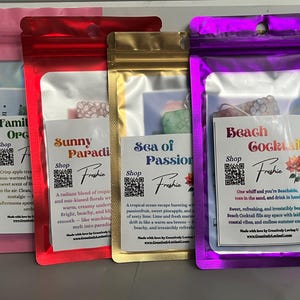 May include: Four colorful pouches containing scented products. Each pouch has a label with a unique name: Family Orchard, Sunny Paradise, Sea of Passion, and Beach Cocktail. The pouches are pink, red, gold, and purple, respectively, and have a clear window.