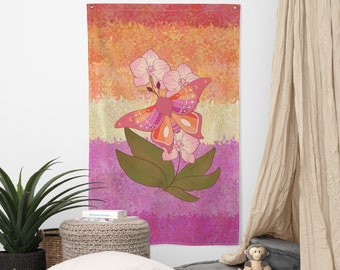 May include: A wall tapestry featuring a butterfly and orchid design. The butterfly is pink, orange, and red, with a floral pattern. The background has horizontal stripes of orange, yellow, and pink. The tapestry is rectangular.