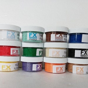 May include: Twelve small jars of colored flocking, labeled with "FX Warehouse Inc." and the color name. The colors are white, teal, brown, blue, red, green, beige, black, yellow, purple, orange, and tan.