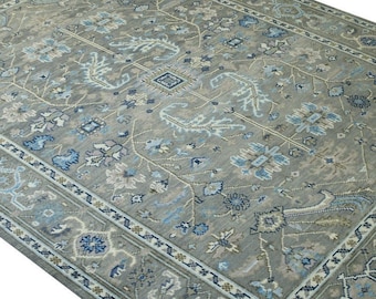 May include: A gray rug with a blue and white floral pattern. The rug has a border with a repeating geometric design.
