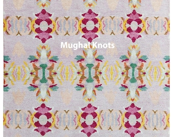 May include: A pink rug with a colorful geometric pattern. The pattern features a repeating design of green, yellow, orange, and red. The rug has a fringe border.