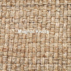 K&ouml;nnte beinhalten: Nahaufnahme eines Naturfaser-Teppichs mit gewebter Textur. Der Teppich besteht aus dickem, braunem Seil und hat eine enge, gleichm&auml;&szlig;ige Webart. Der Text "Mughal Knots" ist in der Mitte des Bildes sichtbar.