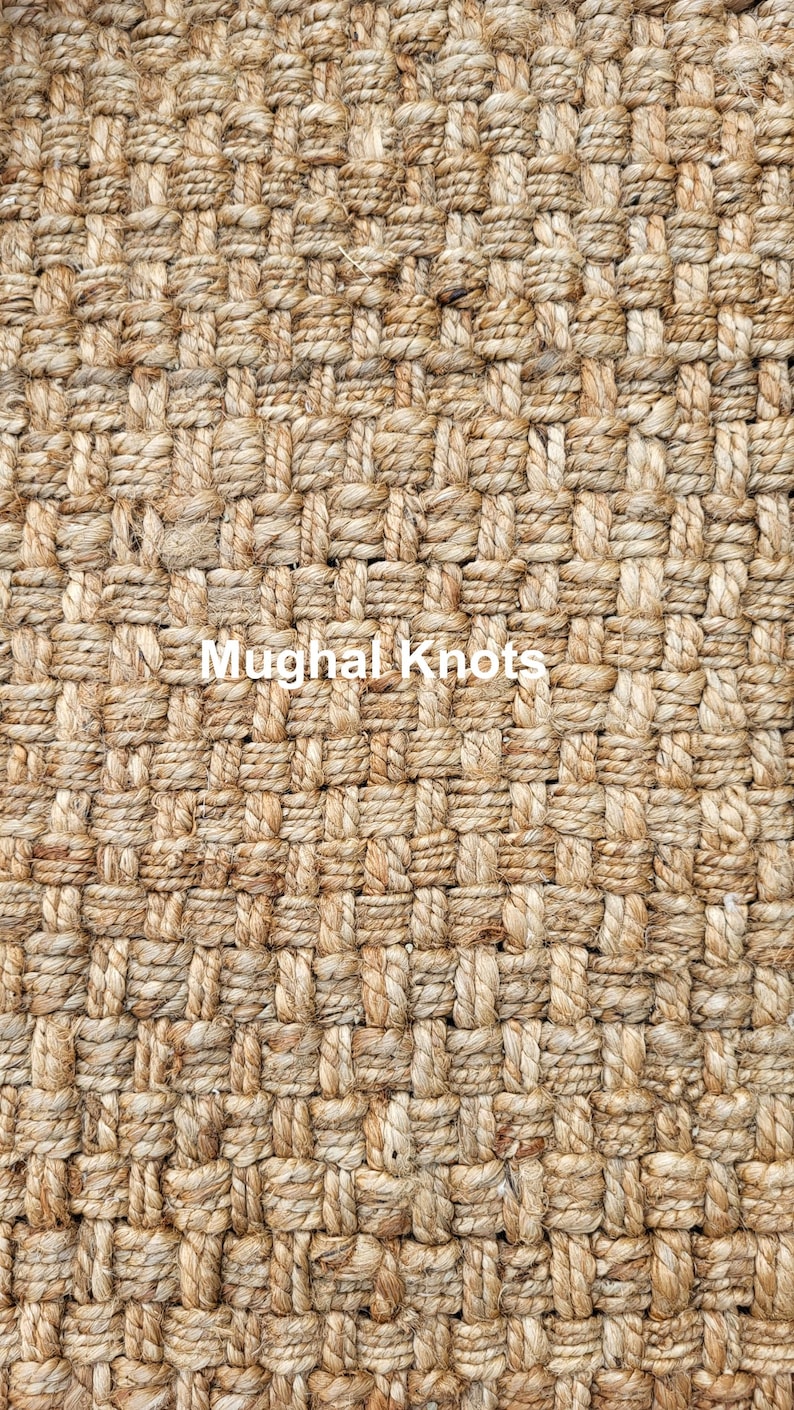 K&ouml;nnte beinhalten: Nahaufnahme eines Naturfaser-Teppichs mit gewebter Textur. Der Teppich besteht aus dickem, braunem Seil und hat eine enge, gleichm&auml;&szlig;ige Webart. Der Text "Mughal Knots" ist in der Mitte des Bildes sichtbar.