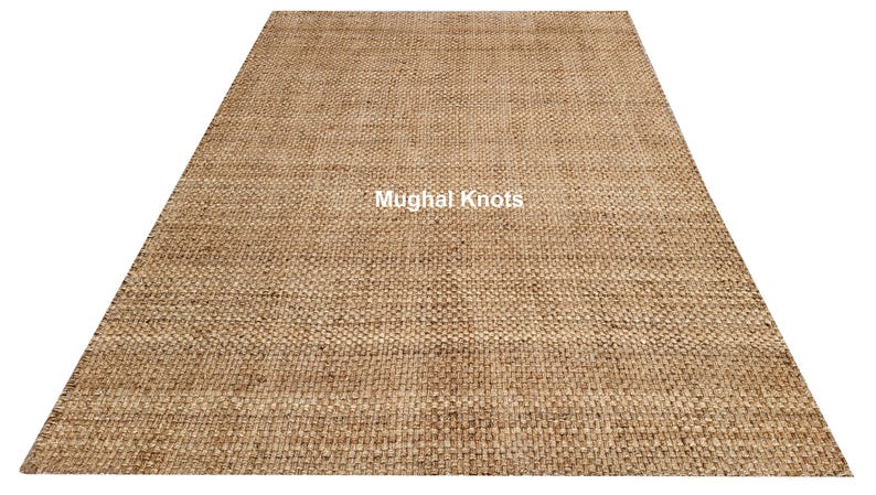 K&ouml;nnte beinhalten: Ein Naturfaser-Teppich in hellbrauner Farbe. Der Teppich ist mit einer dichten, gleichm&auml;&szlig;igen Webart gewebt und hat eine leicht strukturierte Oberfl&auml;che. Der Teppich wird von Mughal Knots hergestellt.