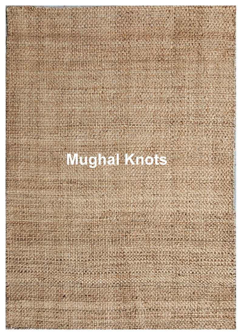 K&ouml;nnte beinhalten: Nahaufnahme eines Naturfaser-Teppichs mit gewebter Struktur. Der Teppich ist hellbraun und hat den Text "Mughal Knots" in wei&szlig; in der Mitte aufgedruckt.