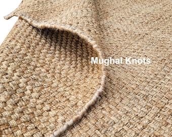 May include: Close-up of a natural fiber rug with a woven texture. The rug is a light brown color and has a slightly frayed edge. The text "Mughal Knots" is visible in the lower right corner of the image.