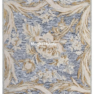 May include: A blue and beige area rug with a floral pattern. The rug features a repeating design of stylized flowers and leaves. The rug has a traditional, elegant look.